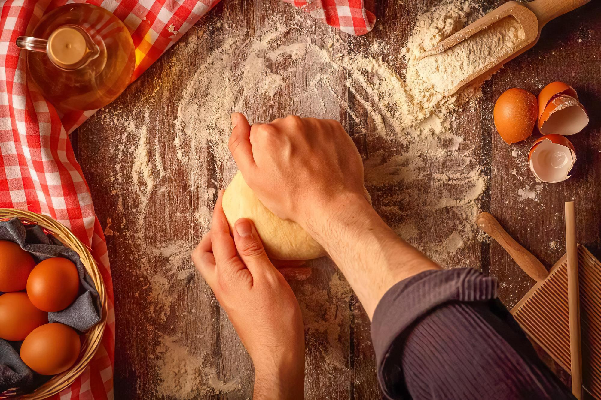 Hands preparing dough on wooden board